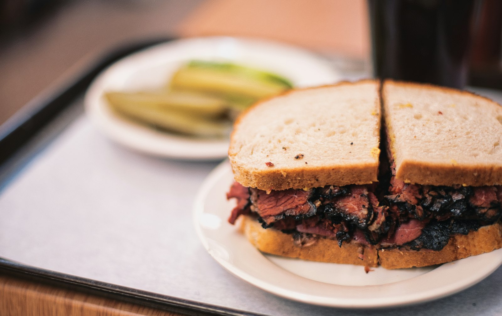 A deli sandwich on a plate with pickle spears
